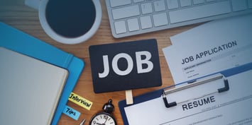 A desk with a coffee cup, keyboard, job application form, resume, and notepad; a scene familiar to anyone who’s sent dozens of applications and heard nothing back. The culprit? Often an untailored resume that today’s employers and applicant tracking systems overlook.